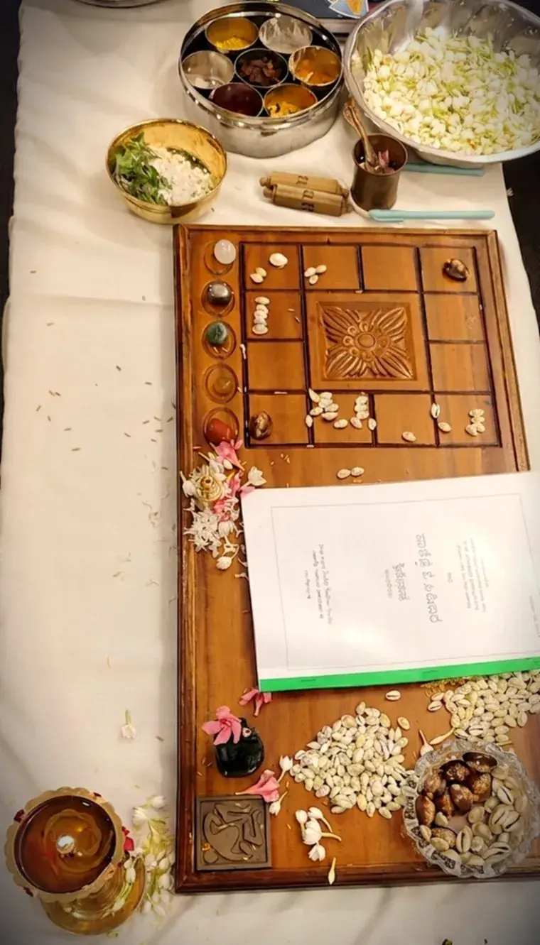 An Ashtamangala Prashna board laid out with cowrie shells, gemstones, jasmine, betel leaves and a lit lamp