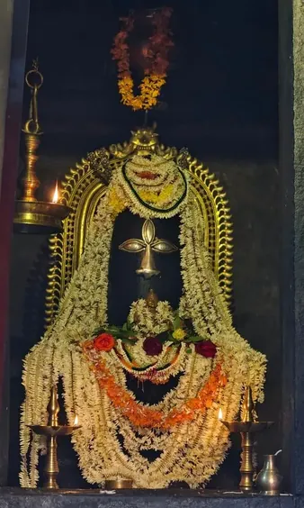 Shiva linga adorned with jasmine garlands and oil lamps